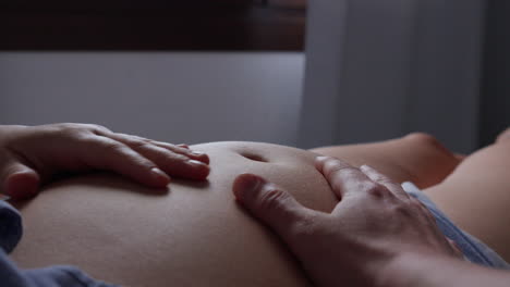 Close-up-of-hands-caressing-pregnant-belly-gently