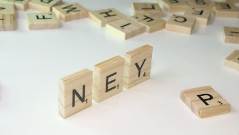 Scrabble-tiles-forming-small-pyramid-spell-word-MONEY-on-white-table