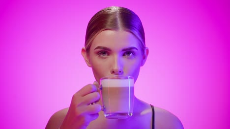 Cute-brunette-woman-takes-a-sip-of-sweet-macchiato-coffee-cup,-studio-shot