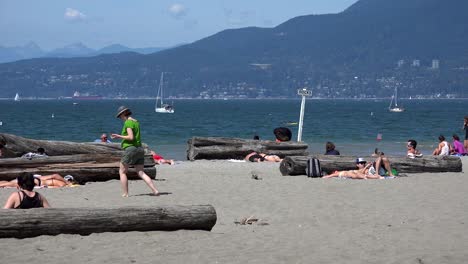 A-lady-walks-on-Kitsilano-Beach-in-Vancouver-with-sunbathers