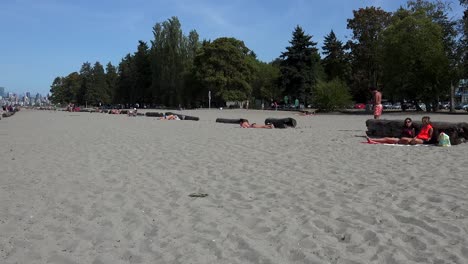 A-muscular-man-walks-on-a-Vancouver-beach,-showing-his-big-muscles