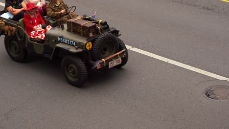 Las-Mujeres-Viajan-En-Un-Vehículo-Militar-Antiguo,-Conducen-Por-La-Calle,-Participan-En-El-Desfile-Del-Día-De-Anzac-En-La-Ciudad-De-Brisbane,-En-Honor-A-Quienes-Sirvieron-Y-Se-Sacrificaron-Durante-Tiempos-De-Guerra.