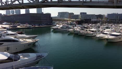 Vista-Aérea-Desde-Un-Dron-Pasando-Por-Debajo-Del-Puente-Del-Puerto-Del-Foro-En-Barcelona,-España