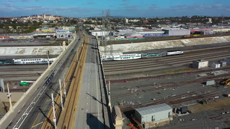 Aerial-pan-shot-following-a-train-moving-under-the-1st-Street-Viaduct-in-Los-Angeles,-USA