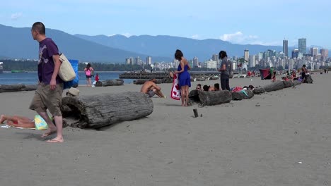 A-man-walks-on-a-Vancouver-beach-with-Vancouver-in-the-background