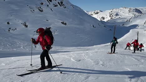 Group-of-cross-country-skiers-carrying-wooden-trail-marker-sticks-up-winter-mountain