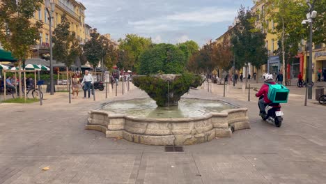 Pedestrians,-scooters-and-fountain-on-Cours-Mirabeau,-Aix-en-Provence