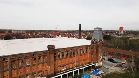 Red-brick-abandoned-building-in-industrial-area-of-city,-aerial-view