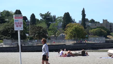 Una-Señora-Camina-Por-Una-Playa-Con-Bañistas