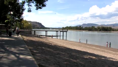 Cyclists-on-sidewalk-by-a-river-beach