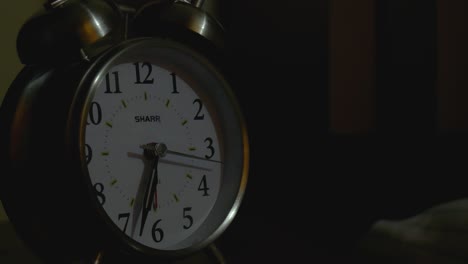 Man-turning-off-analog-alarm-clock-in-bedroom
