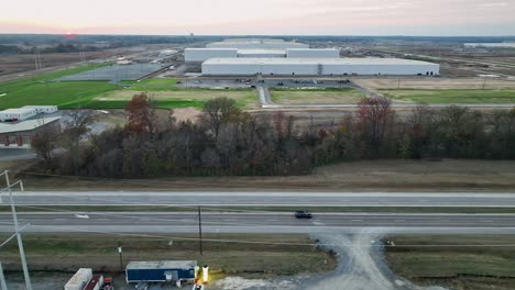 Luftaufnahme-Eines-Fahrzeugs,-Das-Bei-Sonnenuntergang-Vor-Fords-Megacampus,-Blueoval-City,-In-Stanton,-Tennessee,-Fährt