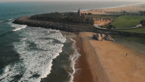 Dolly-Aéreo-Sobre-Las-Olas-En-La-Playa-Con-Revelación-Del-Templo-Costero-En-Chennai