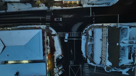 Snow-covered-rooftops-of-buildings-and-warm-lighting-storefront-shops-in-american-town-at-night