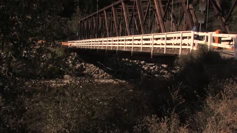 Woman-walks-over-old-bridge-and-looks-down-at-the-river