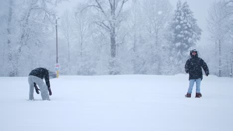 Cheerful-Active-Man-and-Woman-Throwing-Snowballs-at-Each-Other-Having-Fun-Outdoors-During-Winter