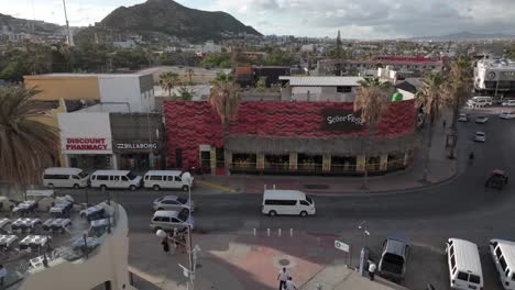 Busy-street-corner-in-Cabo,-Baja-Mexico-with-cars-and-pedestrians,-aerial-view-of-Señor-Frog's-restaurant