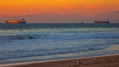 Timelapse,-Anchored-Cargo-Ship-in-Pacific-Ocean,-People-on-Beach-and-Waves-on-Golden-Hour-and-Sunset,-California-USA
