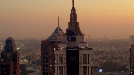Aerial-View-Of-Top-Half-Of-UB-Tower-In-Business-district-in-Bengaluru-with-orange-sunset-skies-in-background
