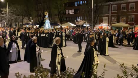 filming-focused-on-the-image-of-the-Virgin-with-her-black-cape-with-gold-embroidery-and-her-shiny-crown-with-her-bearers-following-the-guidelines-of-men-in-suits,-the-amazed-faithful-do-it-well