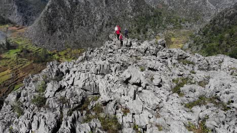 Luftaufnahme-Einer-Gruppe-Von-Erwachsenen,-Die-Auf-Felsen-Stehen-Und-Terrassenfelder-Im-Ha-Giang-Tal,-Vietnam,-Zeigen