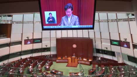 Carrie-Lam,-former-Hong-Kong-chief-executive,-is-seen-on-a-screen-as-she-delivers-her-annual-policy-address-at-the-Legislative-Council-Chamber-in-Hong-Kong