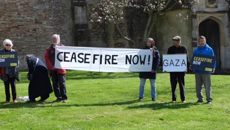 A-group-of-people-with-ceasefire-now-in-Gaza-strip-and-Israel-banners-outside-Wells-Cathedral-in-Somerset-UK