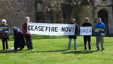 Un-Grupo-De-Personas-Con-Alto-El-Fuego-Ahora-En-La-Franja-De-Gaza-Y-Pancartas-De-Israel-Fuera-De-La-Catedral-De-Wells-En-Somerset,-Reino-Unido