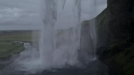 Unter-Einem-Malerischen-Wasserfall-In-Der-Landschaft-Islands-An-Einem-Kalten,-Regnerischen-Tag