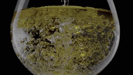 Un-Primer-Plano-De-Aceite-Que-Se-Vierte-En-Agua-Dentro-De-Un-Vaso-Transparente-Sobre-Un-Fondo-Negro