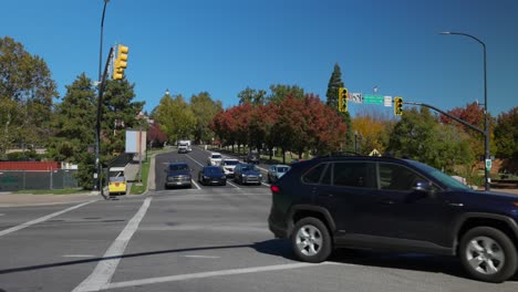 Slow-motion-cars-at-intersection-with-traffic-lights-in-an-American-city-on-sunny-autumn-day