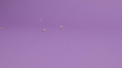 Sesame-seeds-falling-on-violet-background