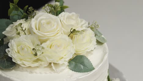 Close-up-of-wedding-cake-made-of-white-fondant,-decorated-with-small-flowers