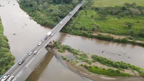 Costa-Rica,-Crocodile-brige,-top-view-bridge-across-the-river,-cars-are-driving-along-the-bridge,-people-are-standing-on-the-bridge,-forest-and-fields