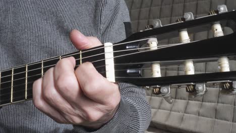 Man-checking-strings-of-acoustic-guitar-close-up