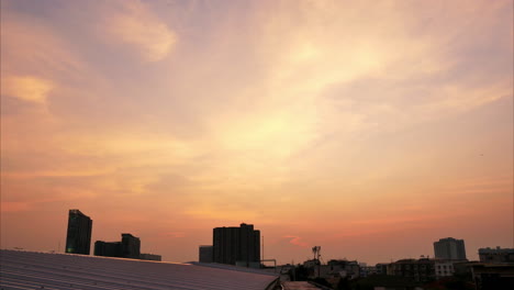 Timelapse-of-the-city's-skyline-as-the-clouds-turn-fiery-red-at-the-setting-of-the-sun-that-turned-the-buildings-at-the-foreground-into-dark-silhouettes,-in-Bangkok,-Thailand
