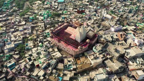 Aerial-drone-view-top-angle-shot-The-drone-camera-is-moving-towards-the-side-where-there-are-many-people-playing-dhuleti-and-where-a-big-temple-is-visible