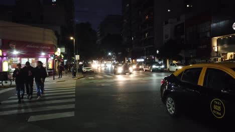 Hyperlapse-Verkehr-Auf-Der-Corrientes-Avenue,-Buenos-Aires,-Stadtnacht,-Menschen-Gehen-An-Einer-Belebten-Straßenkreuzung-Entlang,-Pulsierende-Hauptstadt-Südamerikas