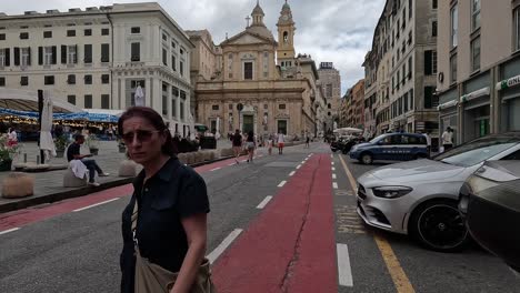 Handheld-footage-walking-next-to-town-square-with-market-stalls,-with-line-of-cars-and-tall-buildings,-in-Italy