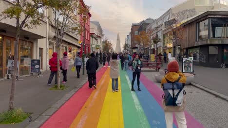 Tourists-take-photos-of-Rainbow-Street-and-Hallgrimskirkja,-Reykjavik