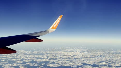 EasyJet-Aircraft-Wing-And-Winglet-In-Flight-Above-Clouds-In-Sky