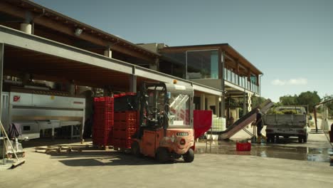 People-working-on-a-vinery,-processing-havested-grapes,-wine-industry-with-automation-machines-in-Italy