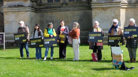 People-holding-ceasefire-now-in-Gaza-strip-and-Israel-banners-sharing-message-during-protest-and-demonstration-outside-Wells-Cathedral-in-Somerset-UK