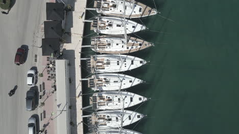 A-drone-captures-Athens,-Greece,-soaring-over-sailboats-with-a-visible-road-filled-with-cars-in-the-scene