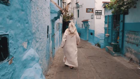 Anciana-Marroquí-Con-Ropa-Tradicional-Caminando-Por-Una-Hermosa-Calle-En-Chefchaouen,-Marruecos