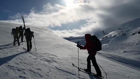 Cross-country-skiers-carrying-trail-markers-while-walking-up-snowy-hill