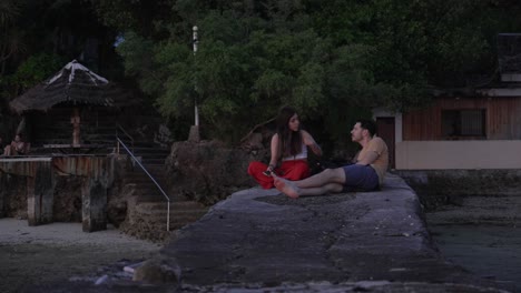 Dos-Jóvenes-Amigos-Conversando-Durante-El-Atardecer-En-Una-Playa-Rocosa-En-Filipinas