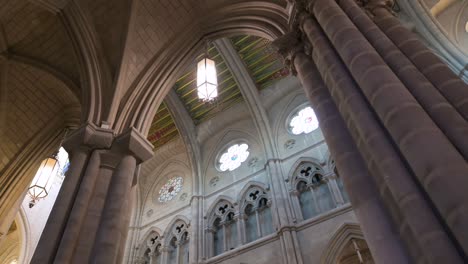 Tilting-shot-interior-view-of-the-Roman-Catholic-Almudena-Cathedral,-completed-and-consecrated-in-1993-by-Pope-John-Paul-II,-as-arches,-columns,-and-pillars-decorate-and-support-the-ceiling-and-dome