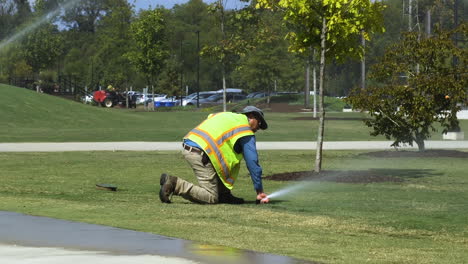 Trabajador-De-Servicios-Públicos-Masculino-Adulto-Arreglando-Y-Ajustando-Rociadores-De-Agua-En-Un-Parque-Público-En-Un-Día-Soleado