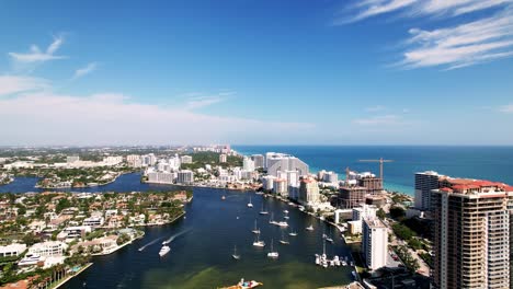 Great-aerial-drone-shot-of-beach-and-sand-with-calm-waters-buildings-on-the-side-blue-water-blue-sky-palm-trees-ft